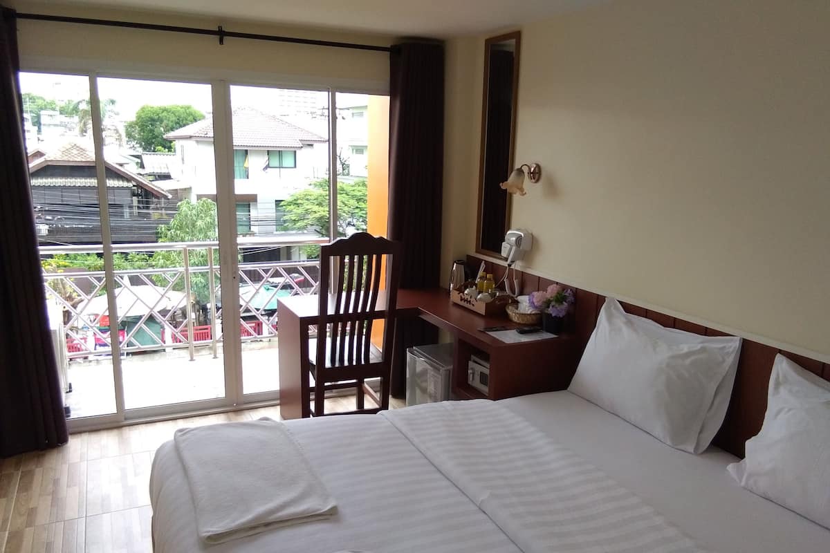 A hotel room with a bed, a desk, a chair, a window, and a view of the outside.