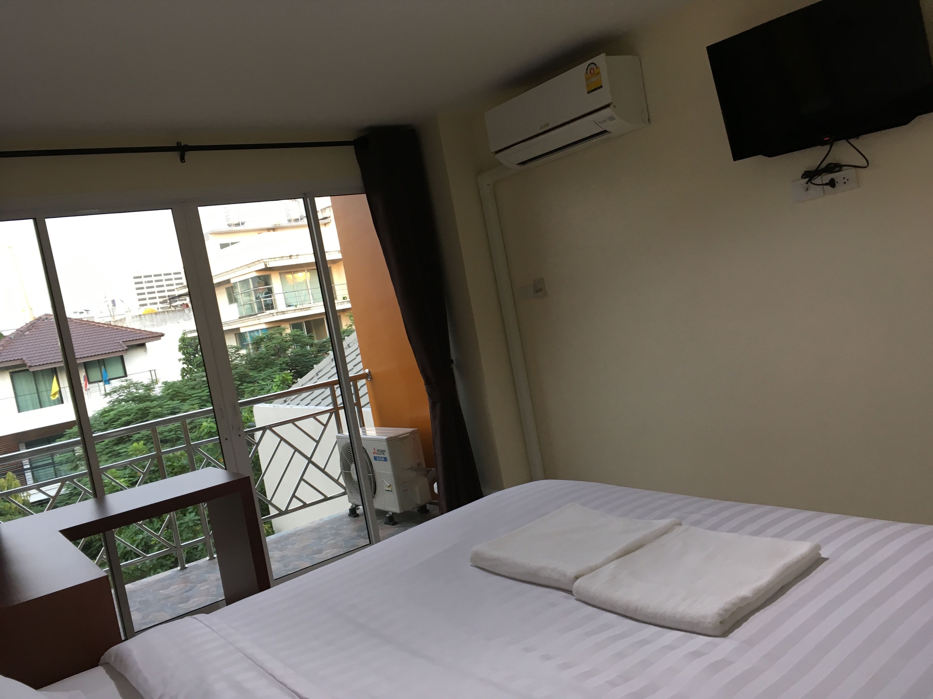 A hotel room with a bed, a desk, a window, and an air conditioning unit.