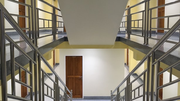 A multi-level interior with metal railings, a central door, and a staircase.
