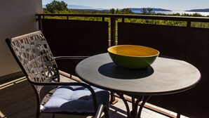 Een balkon met een tafel en stoel, een groene schaal op de tafel, en uitzicht op het landschap.