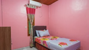 A bedroom with a single bed, pink walls, a wooden ceiling, and a window with a curtain. - Rumah Kost MAPLE Winangun (Manado)