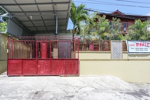 A gated property with a red metal gate, a covered area, and a house with a red roof. - Rumah Kost MAPLE Winangun (Manado)