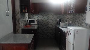 Una cocina compacta con microondas, refrigerador y armarios de madera.