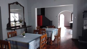 Un comedor con mesas y sillas de madera, un espejo grande y una escalera que sube a otra habitación.