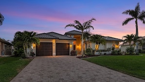 A residential property with a paved driveway, a garage, and a well-maintained lawn. - Gulf Access, Southern Heated Pool, Kayaks, Bikes, Tiki Hut - Villa Salty Shoreline - Roelens (Cape Coral)