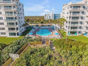 Un resort con piscina central, varios balcones y exuberante jardinería.