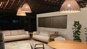 An outdoor patio with a round wooden table, two sofas, and two chairs. - House in condominium by the sea, chicken harbor (high wall)<br> (Porto de Galinhas)