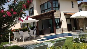 A modern two-story house with a swimming pool, outdoor seating, and a pergola. - House in condominium by the sea, chicken harbor (high wall)<br> (Porto de Galinhas)