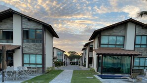 A modern hotel with a central pathway, outdoor seating, and a swimming pool. - House in condominium by the sea, chicken harbor (high wall)<br> (Porto de Galinhas)