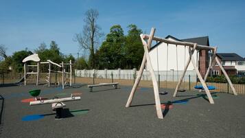 A playground with various equipment including swings, a seesaw, and a climbing structure.