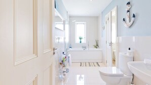 A modern bathroom with a bathtub, toilet, and sink.