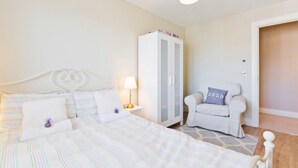 A bedroom with a bed, nightstand, wardrobe, and a chair.