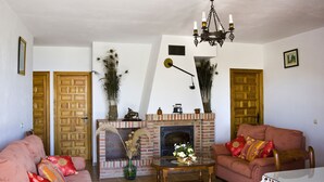 A living room with a fireplace, two sofas, a coffee table, and a chandelier.