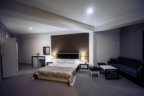 A modern hotel room with a large bed, bedside tables, a desk, a small cabinet, and a sofa. - Hotel Batoni (Tbilisi)