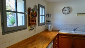 A kitchen with wooden countertops, a built-in dishwasher, a coffee maker, and a clock on the wall.
