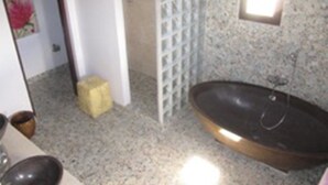 A bathroom with a freestanding bathtub, a small window, and a tiled wall. - De Luxe Duplex (The Valley)