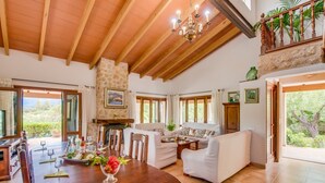 Un salón espacioso con una mesa de comedor de madera, sofás blancos y una chimenea.