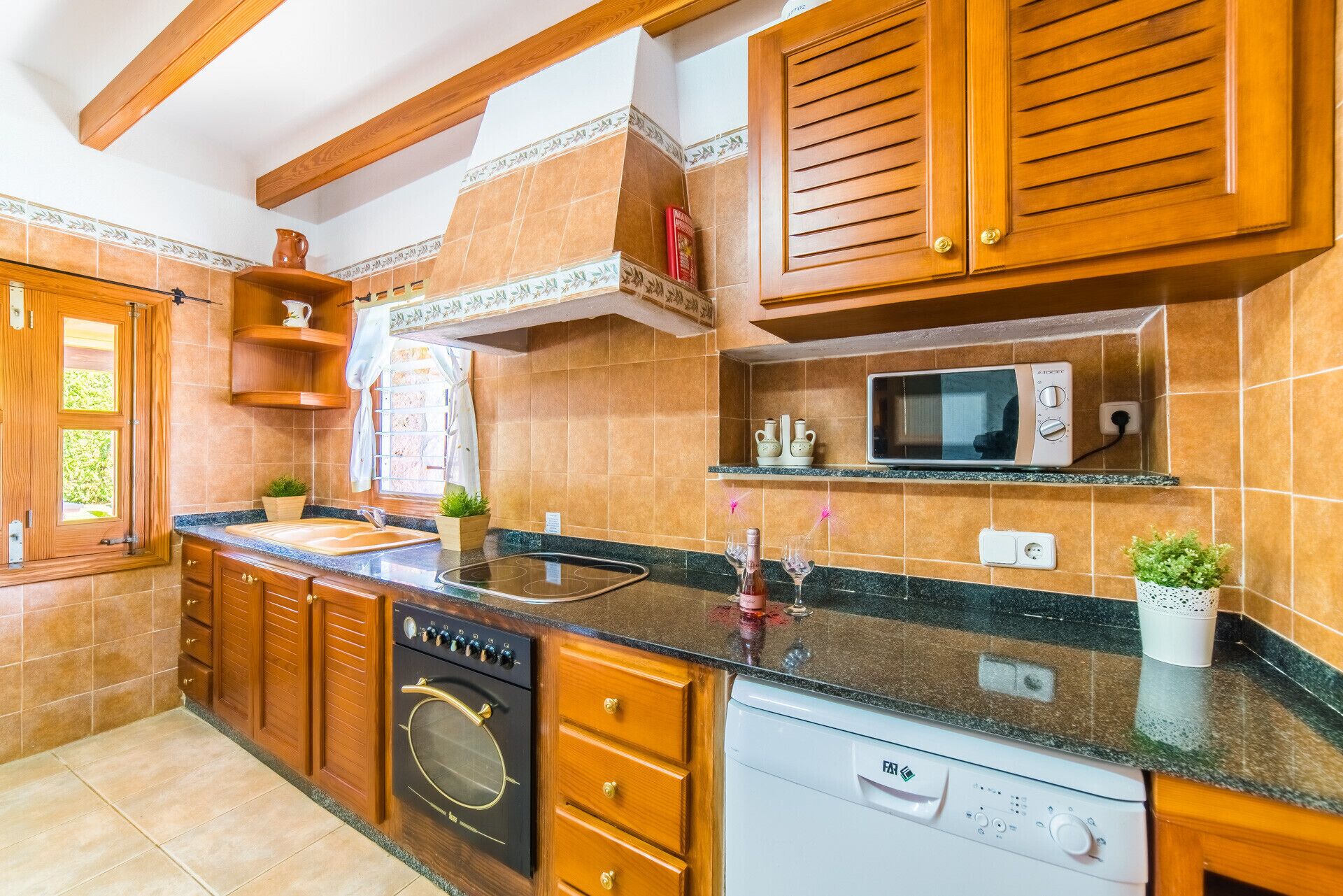 A kitchen with wooden cabinets, a built-in oven, a microwave, and a dishwasher.