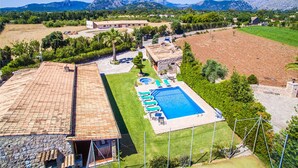 Una propiedad residencial con piscina, una casa de piedra y vistas a las montañas.