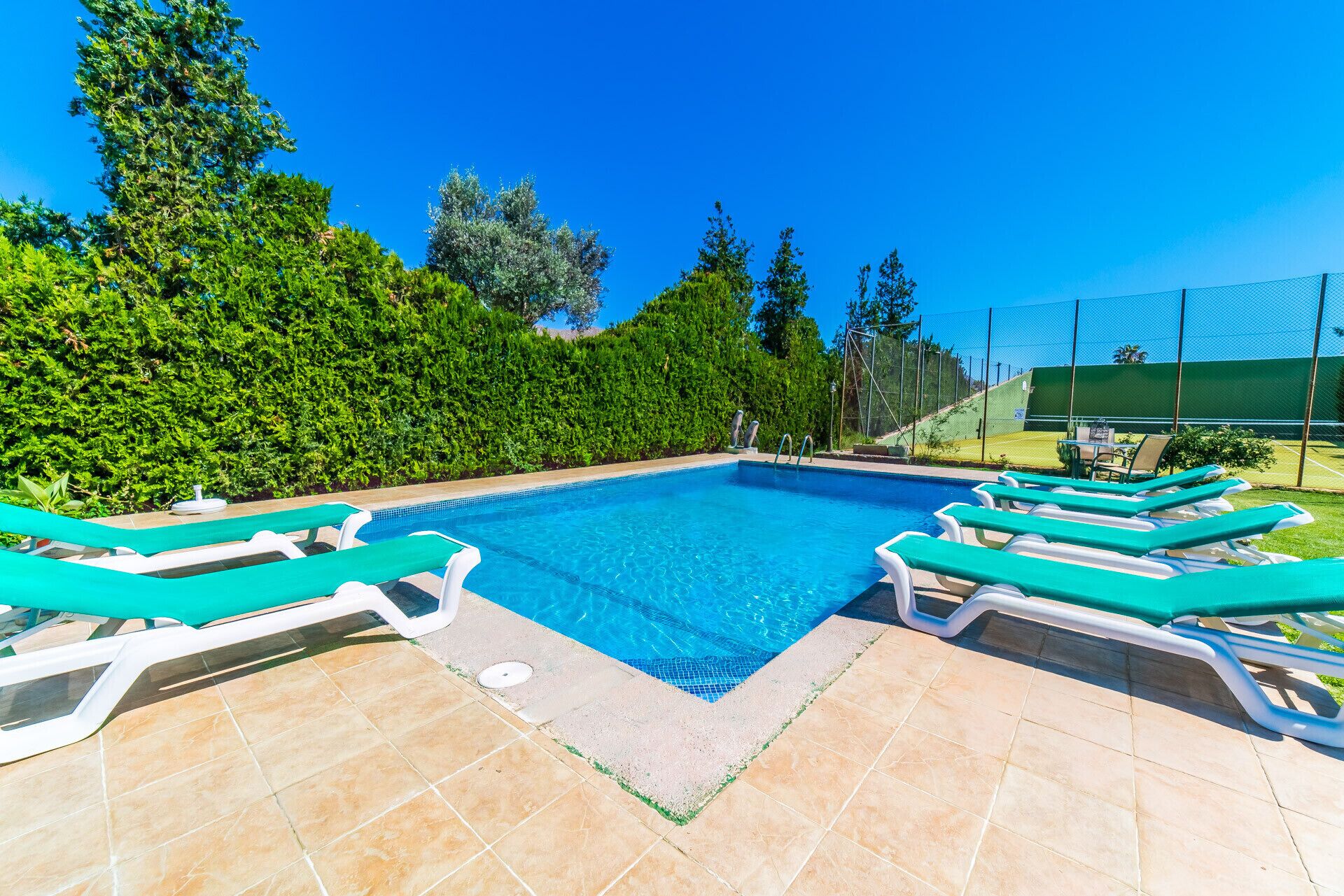 Una piscina con sillas de descanso y un borde con baldosas.