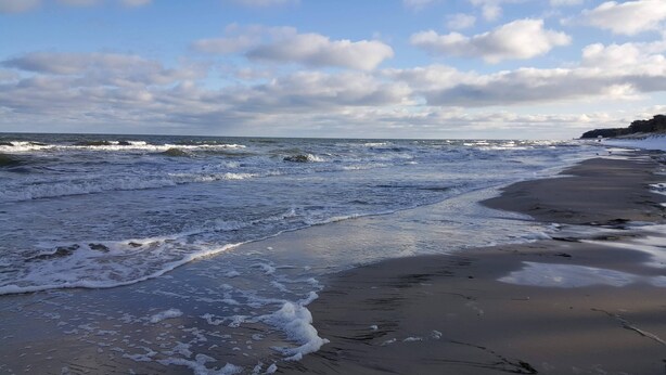 Ein Strand mit Wellen und blauem Himmel.