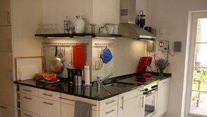 Eine moderne Küche mit weißen Schränken, einer schwarzen Arbeitsplatte und einem eingebauten Backofen.