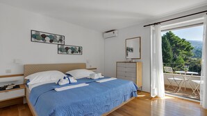 A bedroom with a bed, a nightstand, a dresser, and a balcony with a table and chairs.