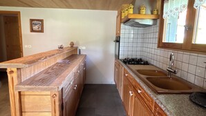 A kitchen with wooden cabinets, a granite countertop, a stove, and a sink. - Ground floor apartment for rent in Bernex for 5 people (Bernex)
