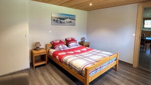 A bedroom with a wooden bed, nightstands, a lamp, and a painting on the wall. - Ground floor apartment for rent in Bernex for 5 people (Bernex)