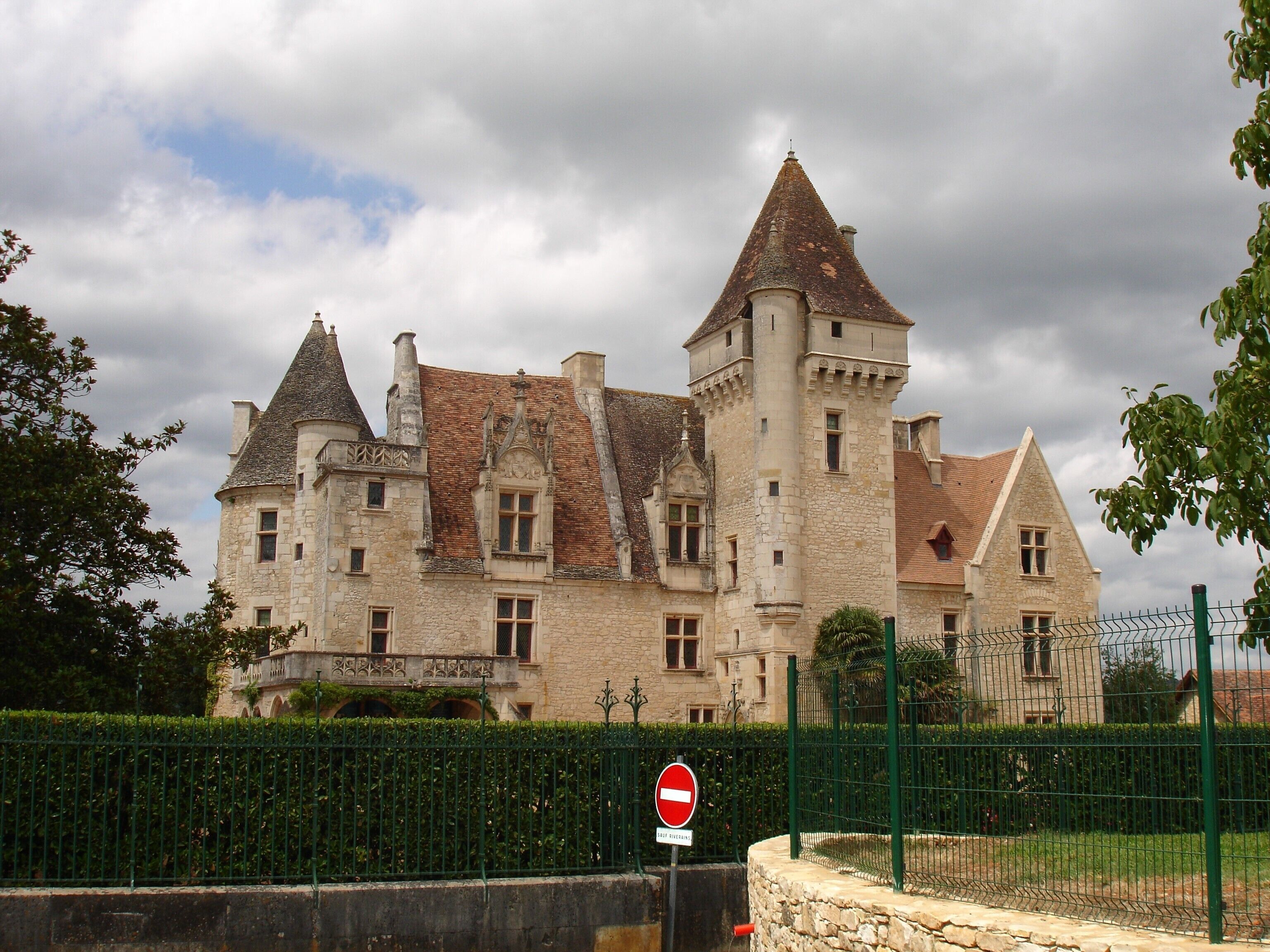 A historic stone building with multiple towers and a gated entrance.