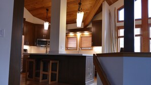 Una cocina moderna con armarios de madera, una isla central con taburetes e iluminación colgante.