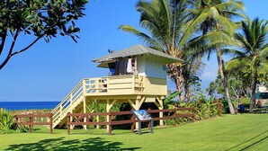 A lifeguard tower with a staircase, surrounded by palm trees and a clear blue sky.