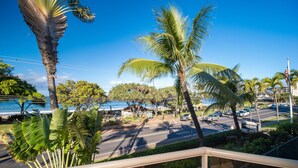 A coastal road with palm trees and a clear blue sky.