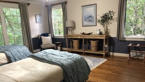 Une chambre à coucher avec un grand lit, une table de chevet, une commode et une fenêtre avec des rideaux.
