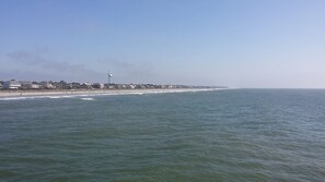 Een kustgezicht met een strand, zee en gebouwen langs de kust.