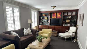 A living room with a brown sofa, yellow armchair, and a coffee table with a plant.