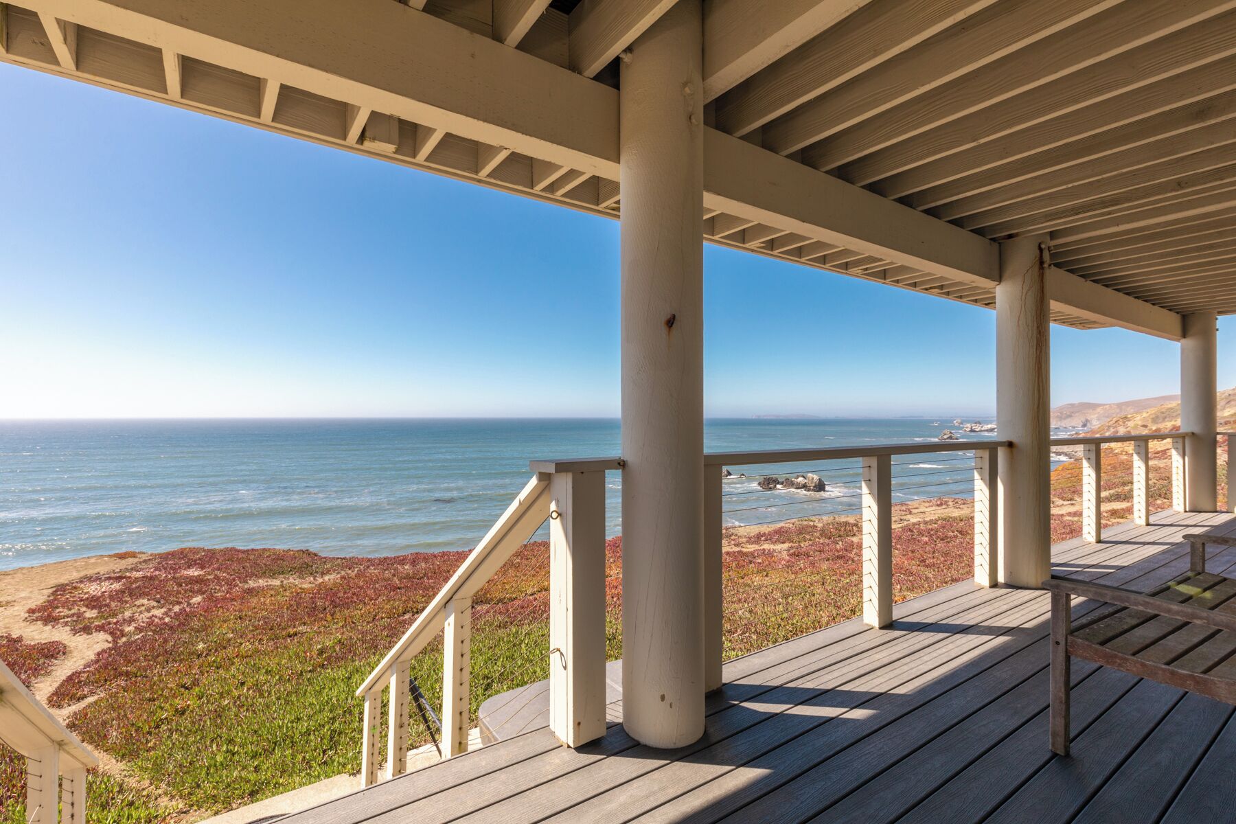 A wooden deck with a view of the ocean and rocky terrain.