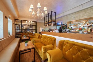 Un bar moderno con asientos tapizados en amarillo, una barra de madera y una variedad de botellas y vasos a la vista.