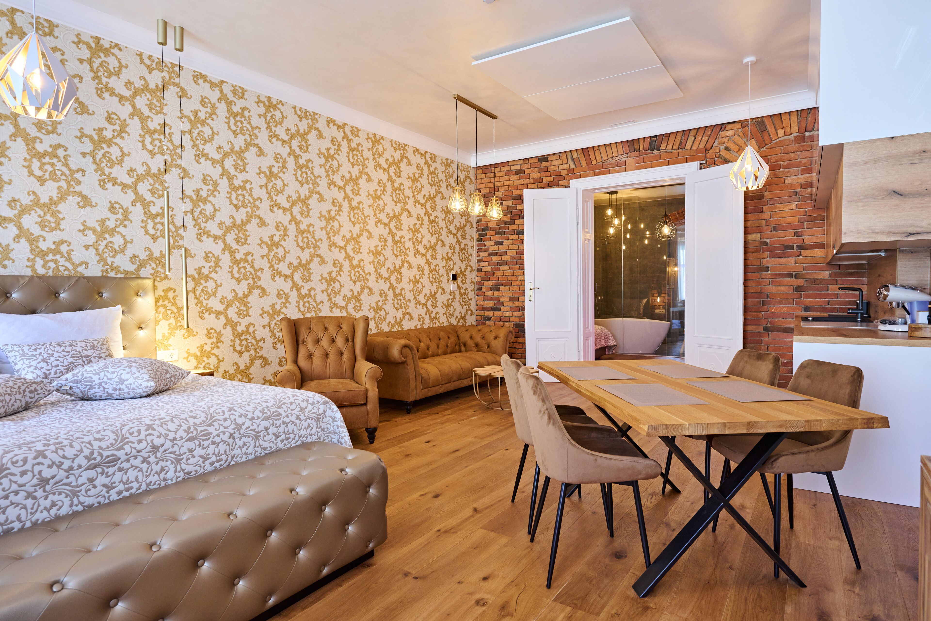 A modern bedroom with a large bed, a sofa, and a dining area with a wooden table and chairs.
