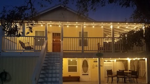 A two-story house with a covered porch, a staircase, and outdoor seating area.