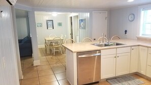 A compact kitchen with a dishwasher, a sink, and a dining area with chairs.