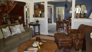 A spacious living room with a ceiling fan, a round wooden coffee table, a brown leather armchair, and a patterned rug. - Beautifully restored Victorian Mountain home furnished with authentic antiques! (Silverton)