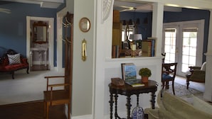 A spacious living room with hardwood flooring, a red sofa, a wooden chair, and a blue and white patterned vase on a table. - Beautifully restored Victorian Mountain home furnished with authentic antiques! (Silverton)
