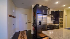 Una cocina moderna con armarios oscuros, electrodomésticos de acero inoxidable y encimera de granito.
