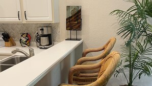 Una cucina con mobili bianchi, una macchina per il caffè e una pianta in vaso.