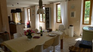 A dining area with a table set for two, a vase with flowers, and a bottle of wine. - Beautifully Restored, Large French Villa On The Banks Of The River Cele. (Cabrerets)