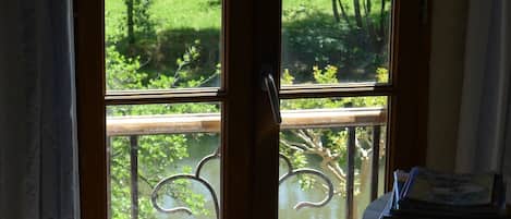 A window with a view of a green landscape and a body of water.