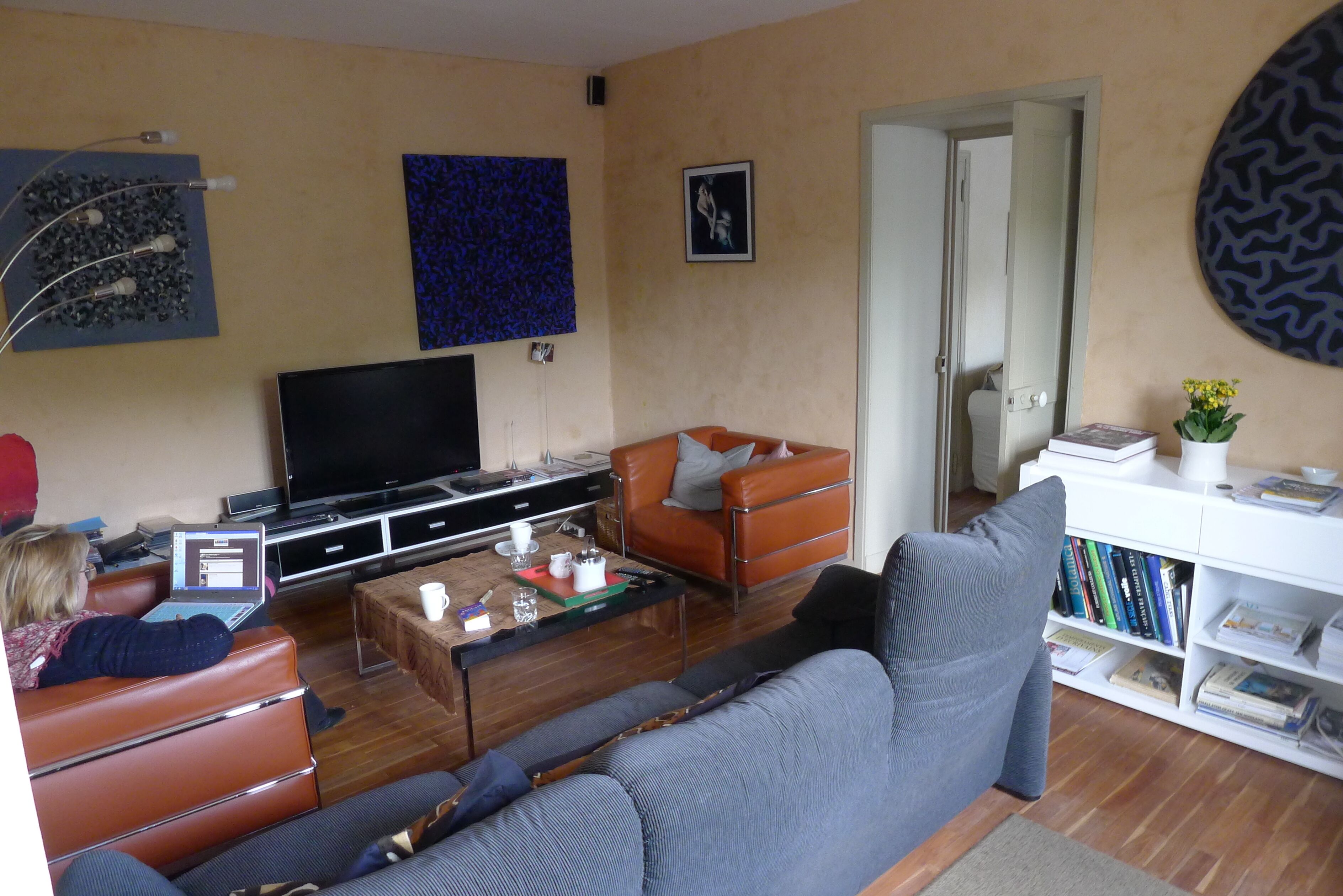 A living room with a sofa, a coffee table, a television, and a bookshelf.