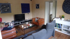 A living room with a sofa, a coffee table, a television, and a bookshelf. - Beautifully Restored, Large French Villa On The Banks Of The River Cele. (Cabrerets)