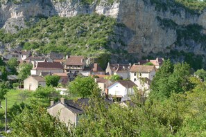 A village with houses nestled against a cliff, surrounded by greenery. - Beautifully Restored, Large French Villa On The Banks Of The River Cele. (Cabrerets)